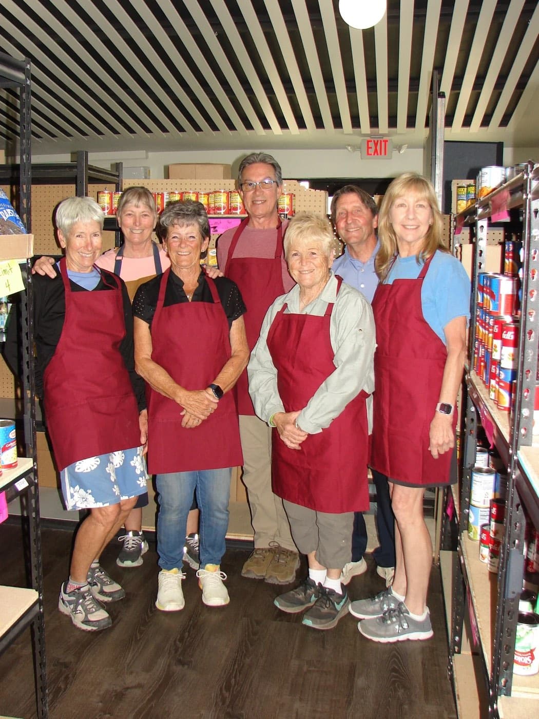 The Monday volunteer team in their aprons between the pantry shelves